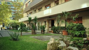 A multi-story hotel with a flat facade, balconies, and a well-maintained garden with various plants and a paved walkway. - A short walk from the Vatican Museums (3 minutes) and St. Peter Church.  (Roma)