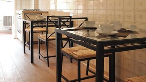 A dining area with a glass table and chairs, a kitchen in the background, and a tiled wall. - A short walk from the Vatican Museums (3 minutes) and St. Peter Church.  (Roma)