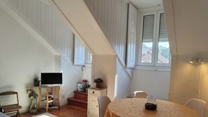 A room with a round table, a TV, a staircase, and a window with blinds. - Sunny 2BR - Av. D. Carlos I, Lisbon (São Bento) (Lisboa)
