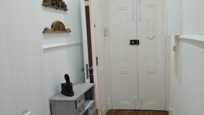 A narrow hallway with white walls and wooden flooring, leading to a set of double doors. - Sunny 2BR - Av. D. Carlos I, Lisbon (São Bento) (Lisboa)