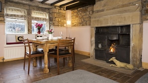 A cozy dining room with a stone fireplace, wooden dining table, and chairs. - Relax in the Heart of Bronte Country (Haworth)