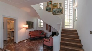A spacious living area with a red sofa, a small table, and a staircase leading to another floor. - Villa Ombrosa 8, Emma Villas (Porano)