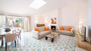 A living room with a sofa, coffee table, and dining area. - Elegant penthouse apartment with amazing terrace! (Roma)