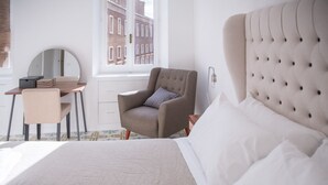 A bedroom with a bed, a desk, a chair, a round mirror, and a window with a view of buildings. - Elegant penthouse apartment with amazing terrace! (Roma)
