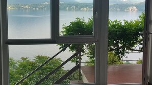 Une pièce dotée d’une grande porte-fenêtre coulissante donnant sur un balcon avec vue sur un lac et des montagnes.