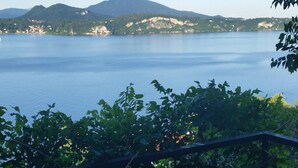 Une table et des chaises sur un balcon donnant sur un lac, avec des montagnes en arrière-plan.