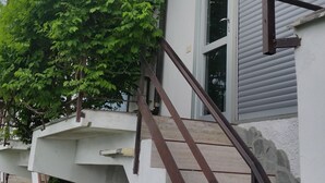 Un immeuble résidentiel doté d’un escalier menant à un balcon, le tout entouré de verdure.