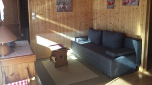 Una habitación acogedora con una pared de madera, un sofá, una mesita y una lámpara.