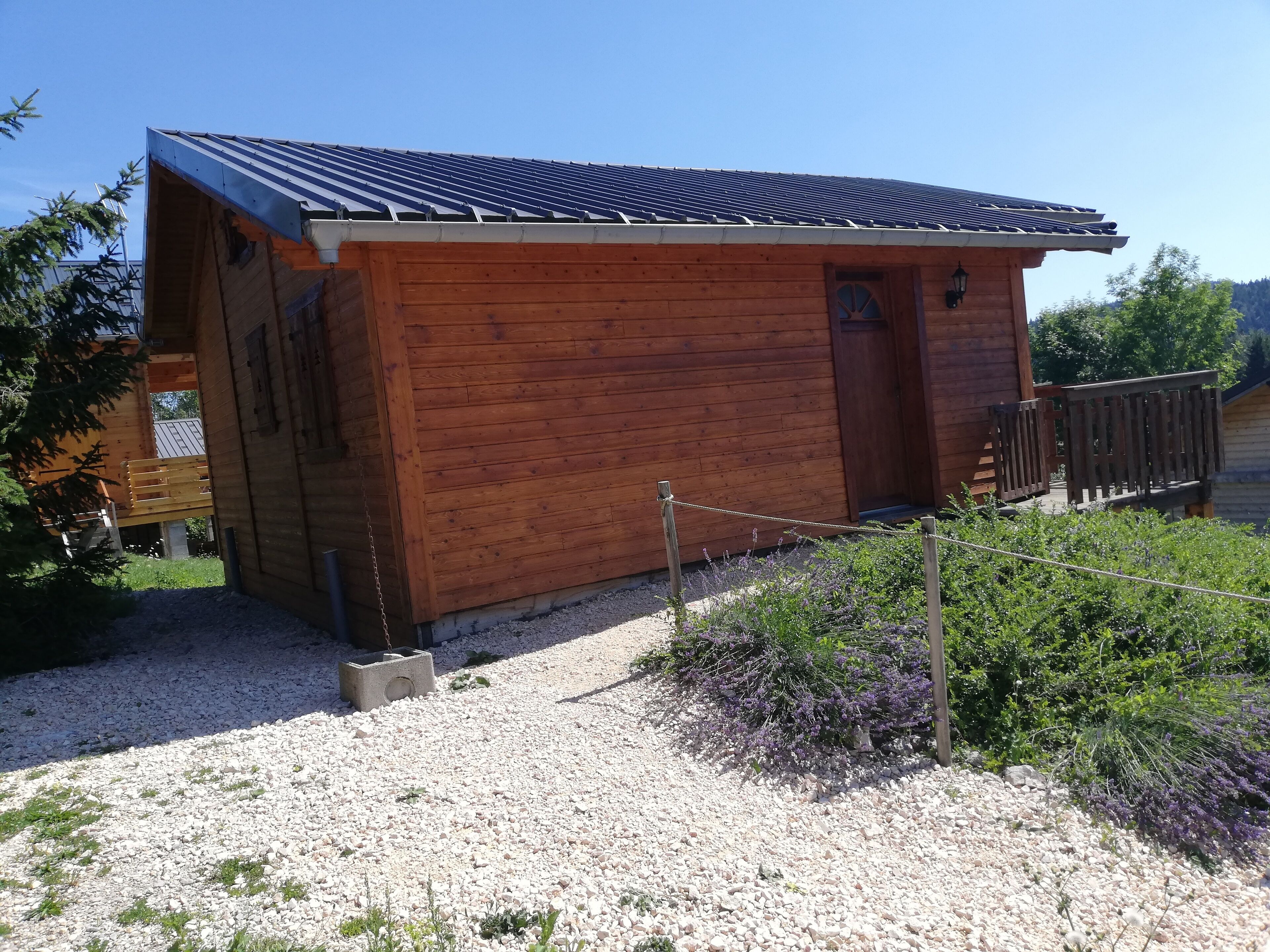A wooden cabin with a sloped roof, a small porch, and a gravel driveway.