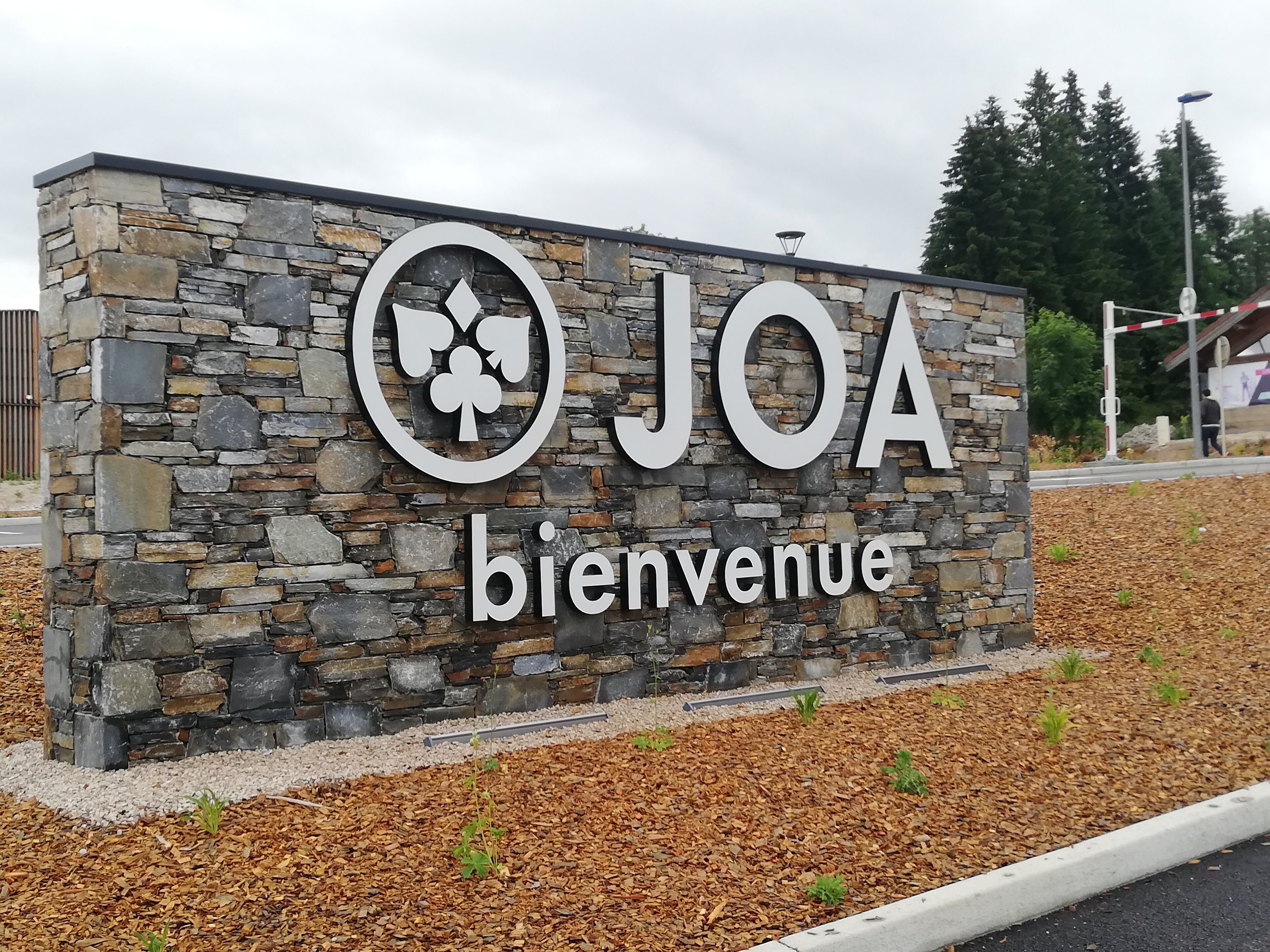 A stone sign with "JOA bienvenue" indicating a welcome sign, likely at a hotel or similar establishment.