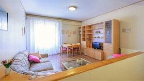 A living room with a sofa, a coffee table, a TV, a bookshelf, and a dining table. - Fantastic holiday home in Rome Free WI-FI 10 minutes from the Vatican (Roma)