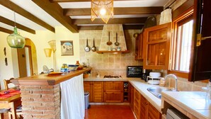 A kitchen with wooden cabinets, a brick column, and a hanging light fixture.