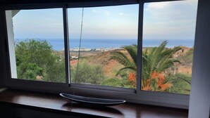 A window with a view of a coastal landscape, including greenery and buildings in the distance. - Chalet with pool in Candelaria (Candelaria)