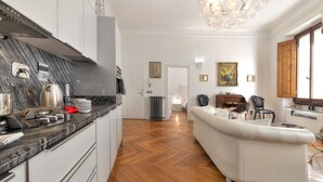 Une cuisine moderne avec un pare-feu en marbre, un canapé blanc et un parquet en bois disposé en motif chevron.