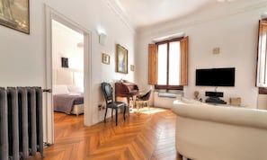 A room with a bed, a desk, a chair, a television, and a radiator.