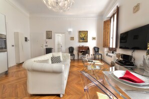 Ein modernes Wohnzimmer mit einem weißen Sofa, einem Glastisch und einem Essbereich mit einem Tisch und Stühlen.