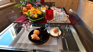 Une table de petit-déjeuner avec une assiette noire, une tasse rouge et un pichet en verre.