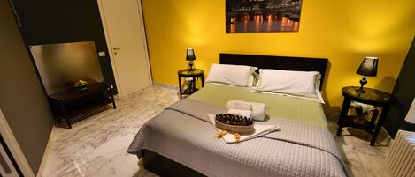Una habitación de hotel con una cama, dos mesitas de noche, un atril, un cuadro y suelo de mármol.