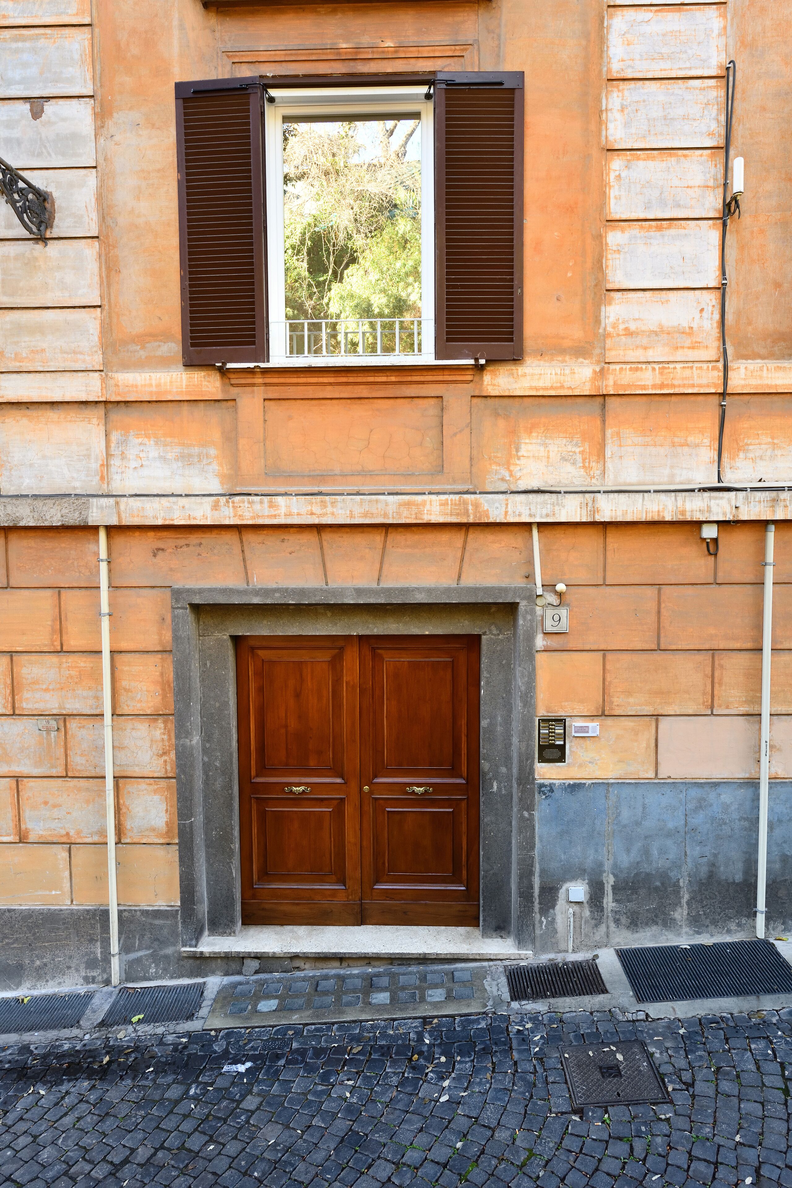 A building with a wooden double door and a window with brown shutters.