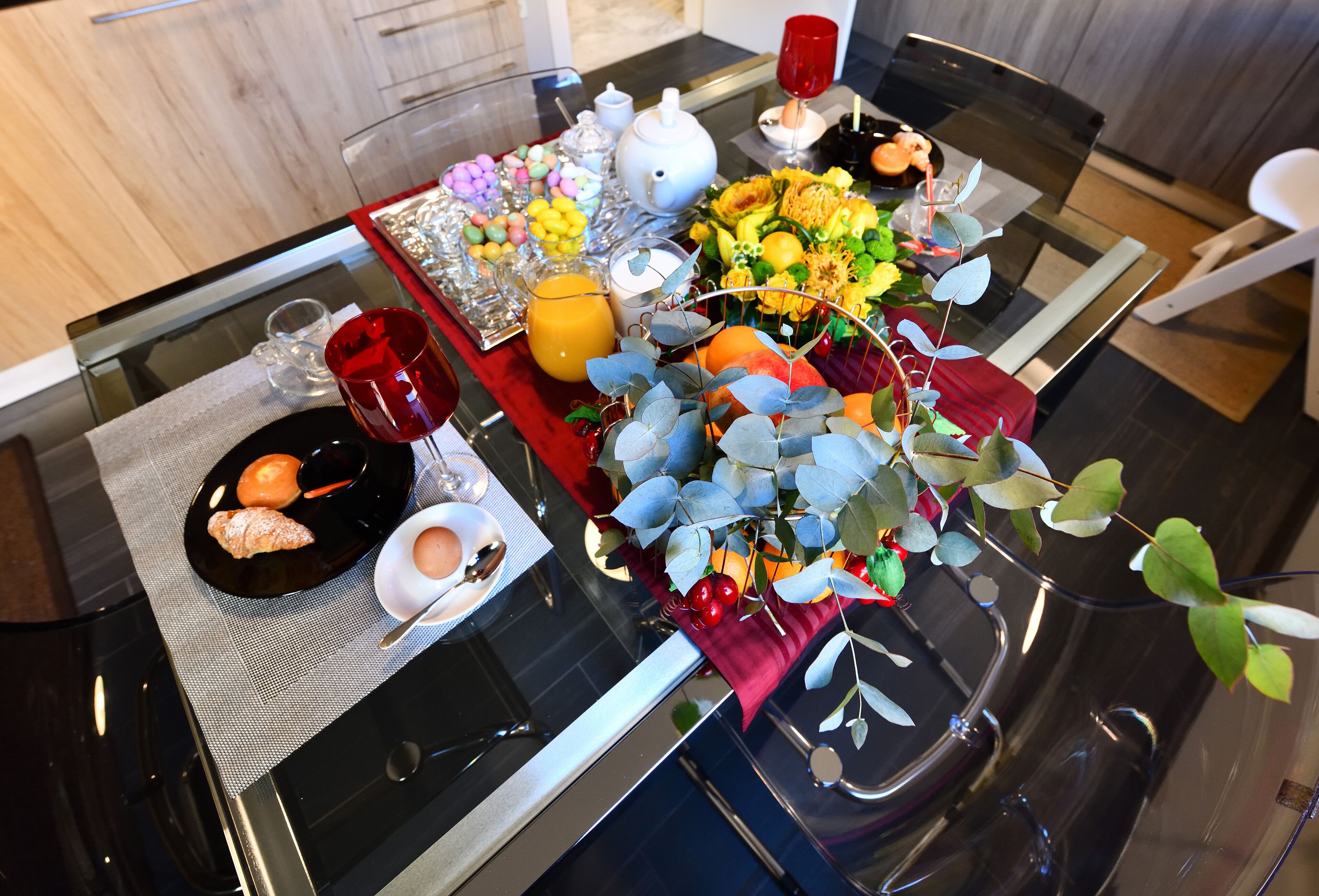 Une table de petit-déjeuner avec une variété d’aliments, notamment des viennoiseries, des fruits et un arrangement floral.