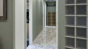 Un couloir doté d’un sol en marbre, une porte donnant sur une pièce et un mur en blocs de verre.