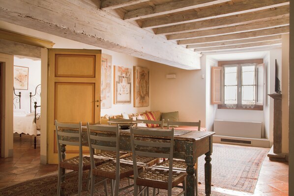 A dining area with a wooden table and chairs, a patterned rug, and artwork on the walls. - "Renaissance Retreat" by WP Relais , Palazzo Uguccioni, in Piazza della Signoria (Firenze)
