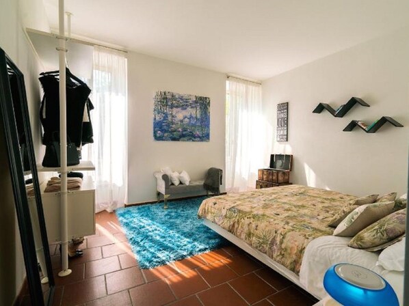 Une chambre à coucher avec un lit, un tapis bleu, un tableau et une armoire.