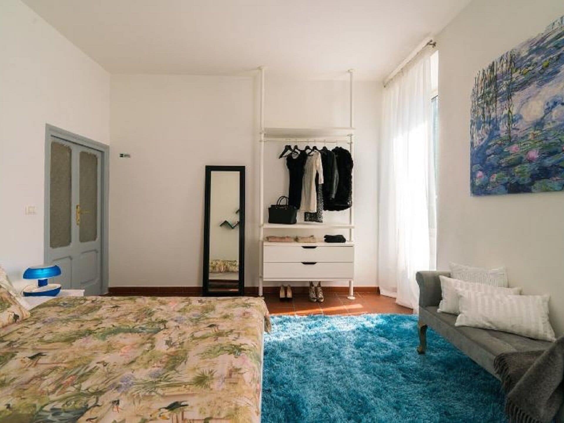 A bedroom with a bed, a dresser, a chair, and a painting on the wall.