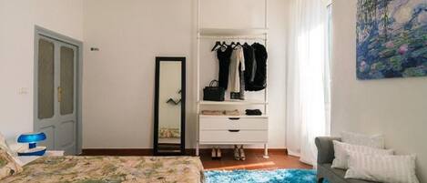 A bedroom with a bed, a dresser, a chair, and a painting on the wall.