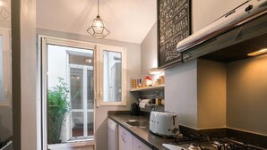 A compact kitchen with a gas stove, a toaster, and a window with a view of greenery outside. - Garibaldi Roof Garden - Terrace with spectacular views of S. Peter and Gianicolo (Roma)