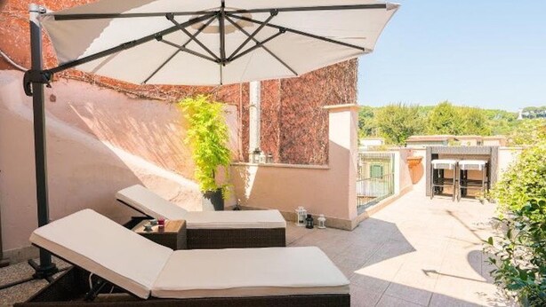 A rooftop terrace with two lounge chairs, a large umbrella, and a potted plant. - Garibaldi Roof Garden - Terrace with spectacular views of S. Peter and Gianicolo (Roma)