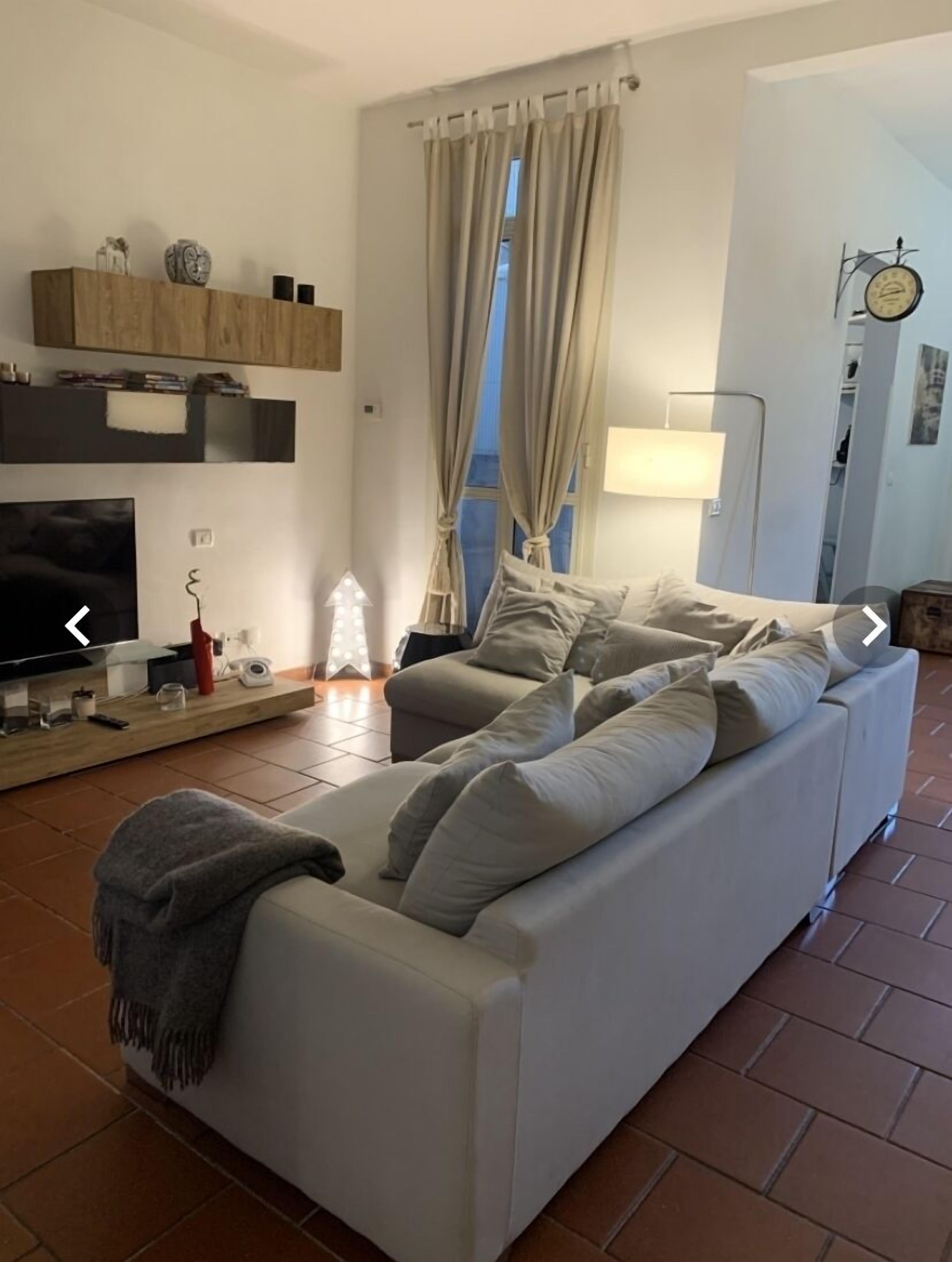 A living room with a sofa, TV, and a lamp.