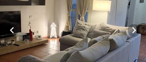 A living room with a sofa, TV, and a lamp.