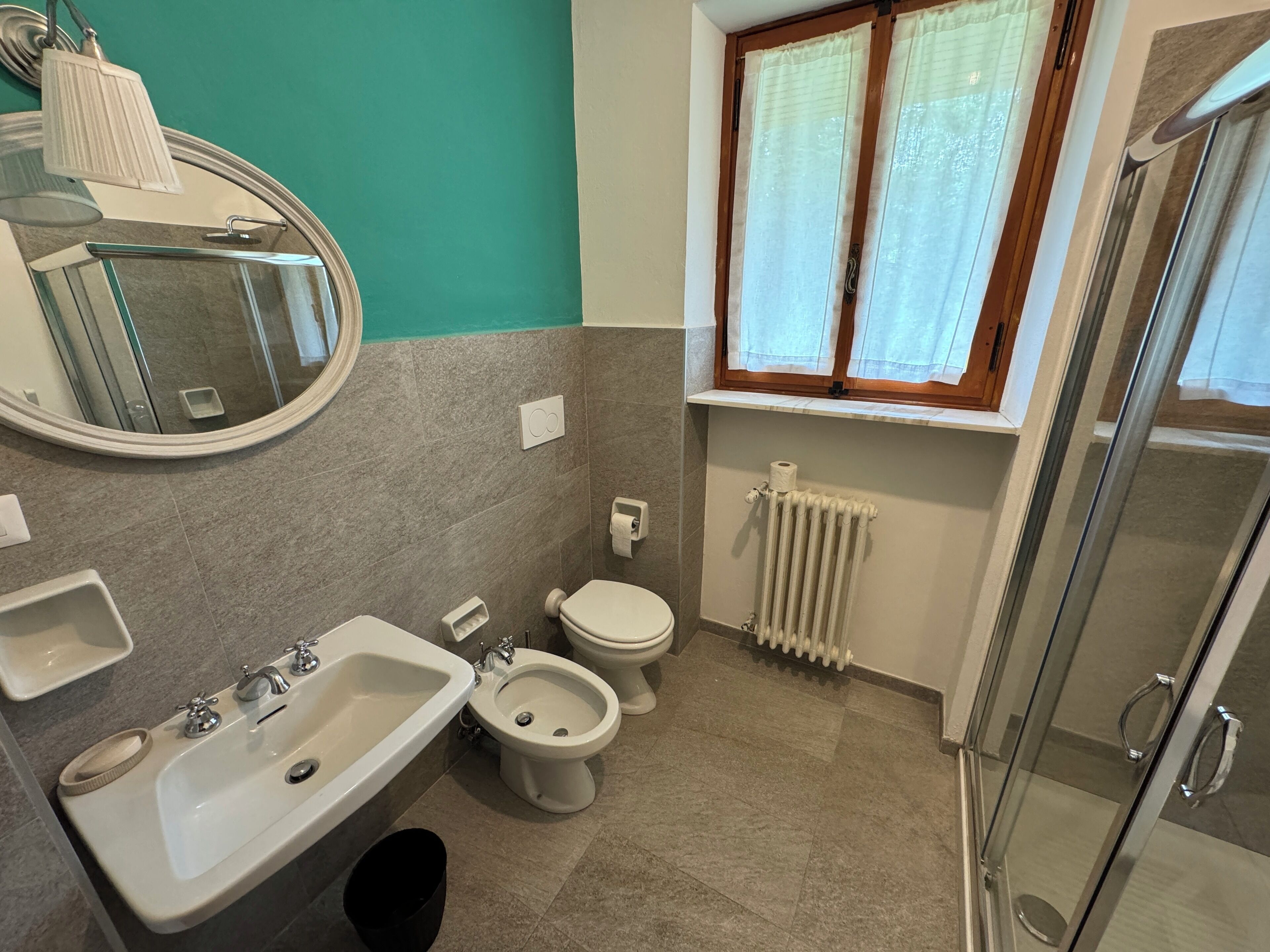 Een badkamer met een wastafel, een bidet, toilet en een douchecabine van glas.