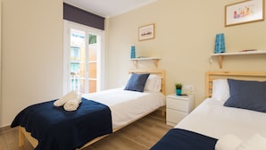 A hotel room with two beds, a small bedside table, a nightstand, a window, and a door. - Brand New Apartment Near Camp Nou & Fira Barcelona (L'Hospitalet de Llobregat)