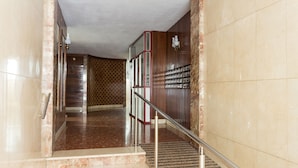 A marble staircase with a metal handrail leading to a wooden door. - Brand New Apartment Near Camp Nou & Fira Barcelona (L'Hospitalet de Llobregat)