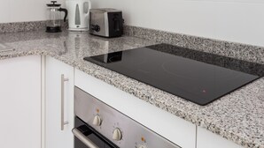 A kitchen with a built-in induction cooktop, a coffee maker, and a toaster. - Brand New Apartment Near Camp Nou & Fira Barcelona (L'Hospitalet de Llobregat)
