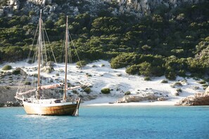 A boat anchored near a rocky coastline with sparse vegetation. - Beautiful apartment sea view - Residence Eolo (Santa Teresa Gallura)
