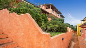 Una escalera que lleva a un edificio con fachada de terracota, rodeado de follaje.