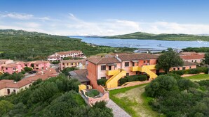 Un pueblo costero con casas escalonadas, un edificio amarillo destacado y un puerto deportivo con barcos.