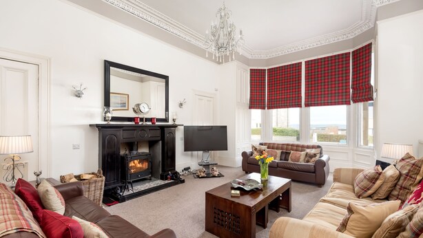 A living room with a fireplace, sofas, a coffee table, and a television.