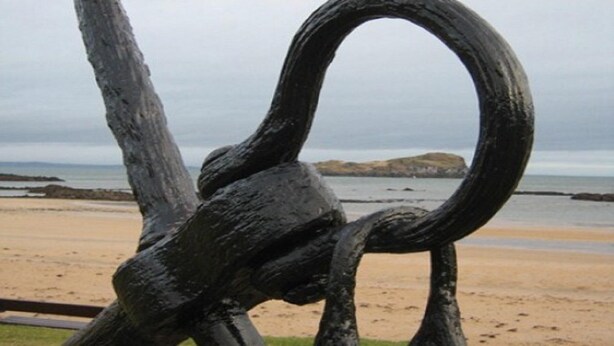 A black metal sculpture with a looped design, located on a sandy beach with a rocky outcrop in the background. - "Fraser's", Marine Lodge, Private Parking, Big 2 Bed Ground Floor for Golf / Sea (North Berwick)