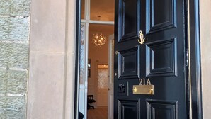 A black door with the number 21A, a small step leading up to it, and a patterned mat at the entrance.