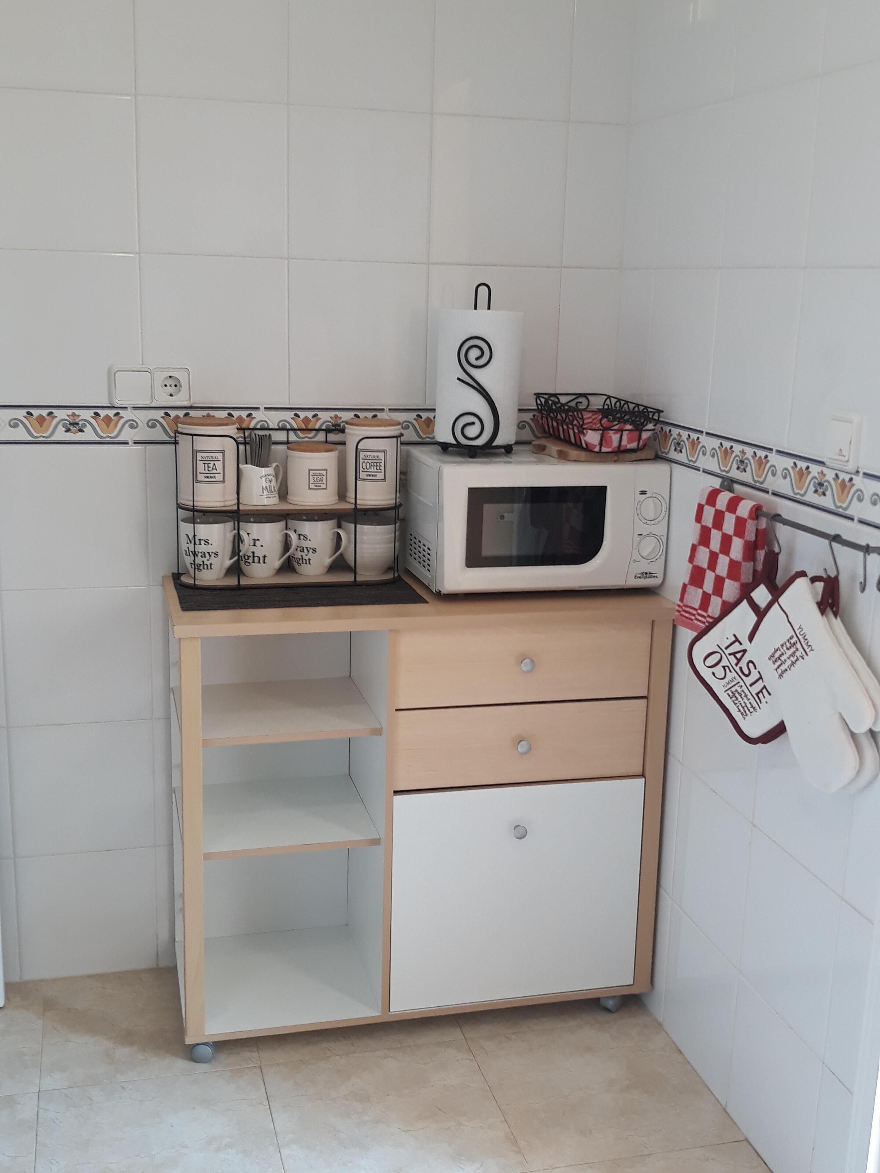 A kitchen with a microwave, a coffee maker, and a mug rack.