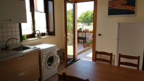 Una cocina con lavadora, un lavamanos y una ventana con cortinas.