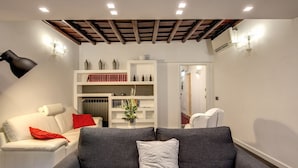 Una sala de estar moderna con un sofá gris, sillones blancos y una estantería.