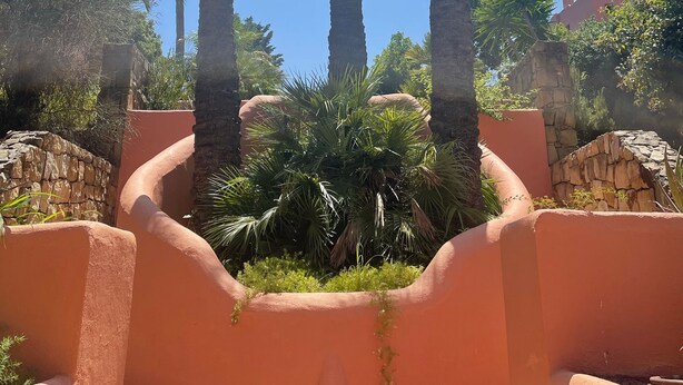 A courtyard with tall palm trees and a stone wall. - Golf, Tennis, Paddle Tennis, Gym, 4 pools including heated, (Ojen)