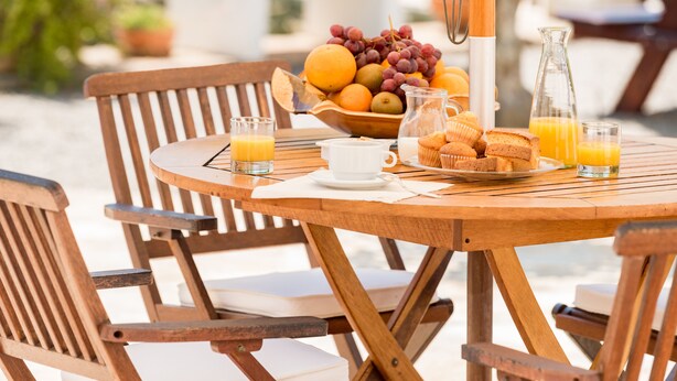 Een houten tafel met ontbijtartikelen, zoals fruit, muffins en sinaasappelsap.
