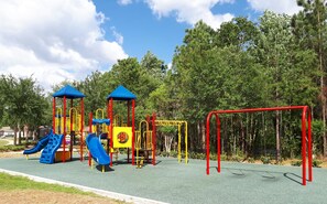 Children can play and exercise on the playground's slides and climbing frames surrounded by lush greenery.