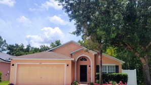 A single-story house with a garage, a front door, and a small front yard with red mulch and greenery. - Luxury Executive Villa with Private Pool, Spa & Games Room 10 miles from Disney (Davenport)
